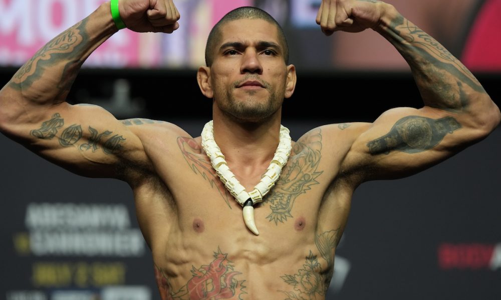 Alex Poatan flexiona os músculos ao subir na balança da pesagem cerimonial do UFC 276.