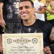 Charles do Bronxs posa para fotos após receber o certificado de grau preto de muay thai
