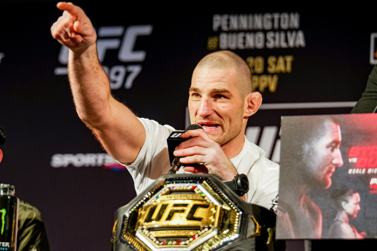 Sean Strickland com o dedo em riste ao lado do cinturão na coletiva do UFC 297